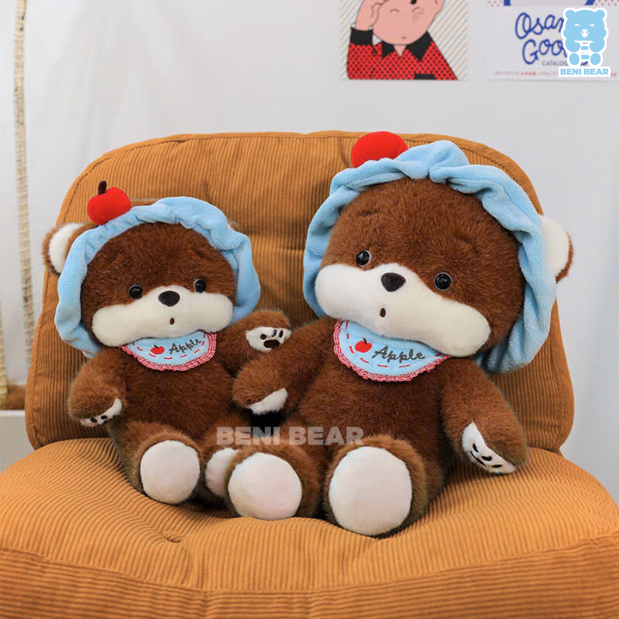 Hai bé gấu bông chó baby ngồi cạnh nhau trên ghế, tay chân bụ tròn, mũ quả táo ngộ nghĩnh