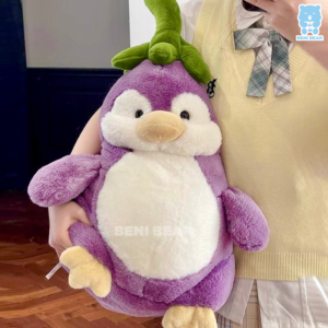 Gấu bông cánh cụt cà tím size lớn được ôm trên tay, thân tím tròn bụ bẫm, lá xanh cực đáng yêu