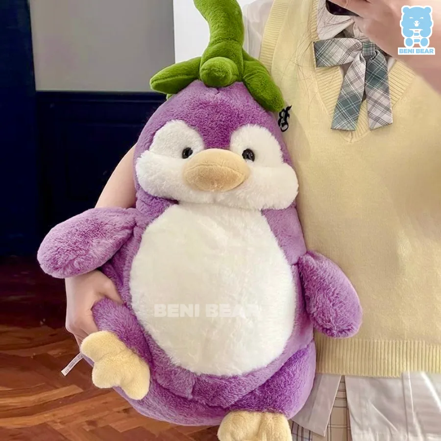 Gấu bông cánh cụt cà tím size lớn được ôm trên tay, thân tím tròn bụ bẫm, lá xanh cực đáng yêu
