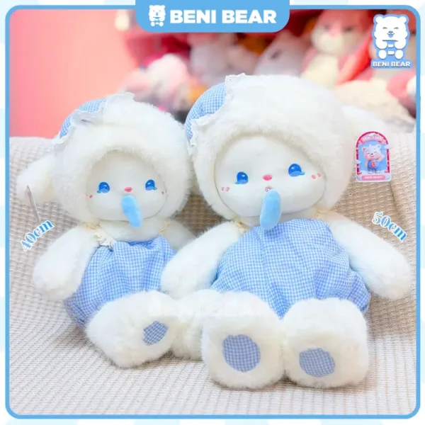 Cừu trắng mặc yếm xanh kẻ caro đang ngồi với kiểu dáng xinh xắn.