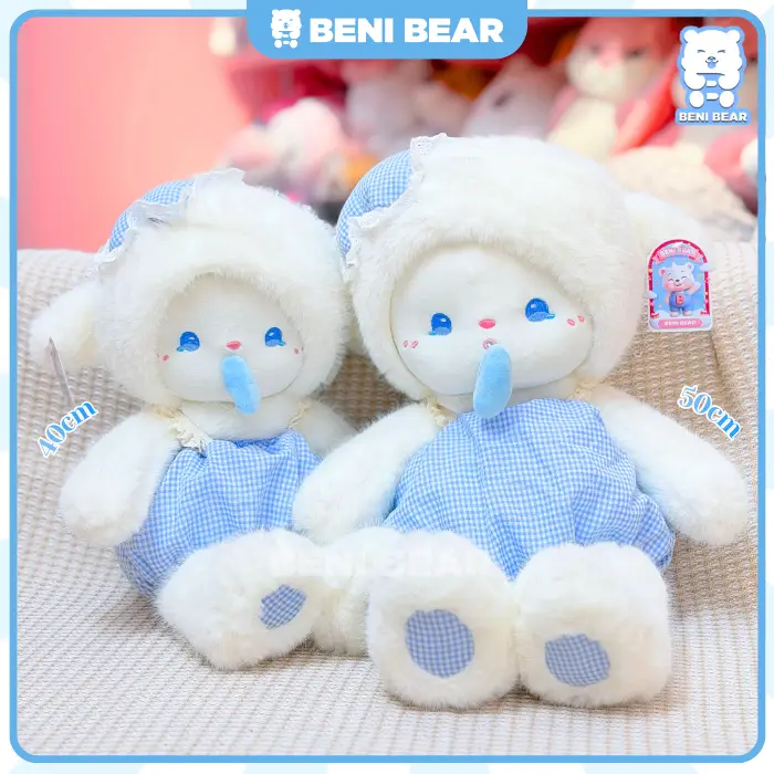 Cừu trắng mặc yếm xanh kẻ caro đang ngồi với kiểu dáng xinh xắn.